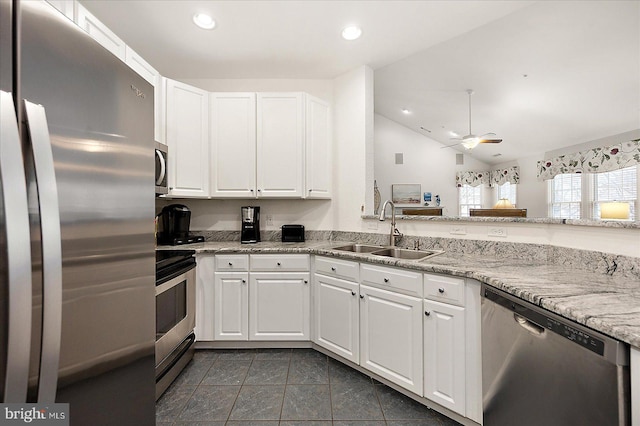 kitchen with lofted ceiling, sink, appliances with stainless steel finishes, light stone countertops, and white cabinets