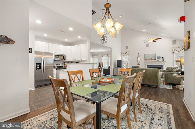 dining area featuring dark hardwood / wood-style flooring, ceiling fan with notable chandelier, and high vaulted ceiling