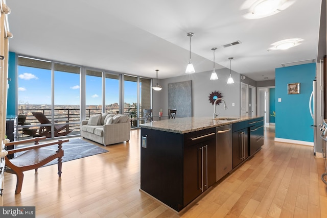 kitchen featuring hanging light fixtures, floor to ceiling windows, sink, and a center island with sink