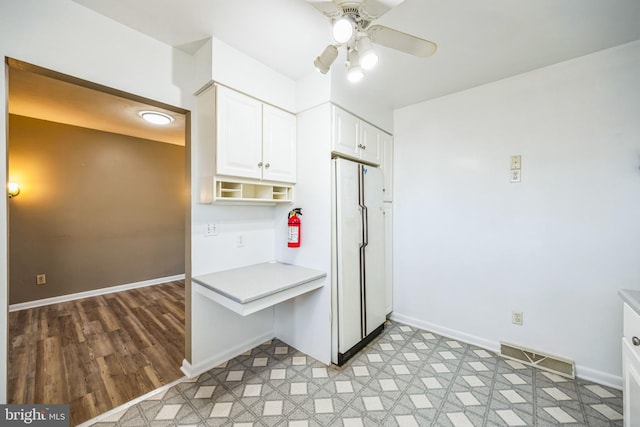 kitchen with light countertops, freestanding refrigerator, white cabinetry, and baseboards