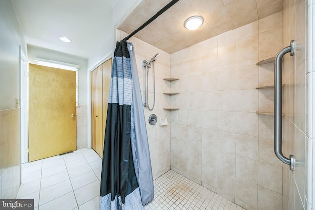 bathroom with a stall shower, tile patterned flooring, and tile walls