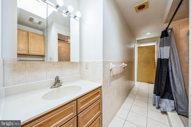 bathroom with visible vents, a wainscoted wall, tile patterned flooring, vanity, and tile walls