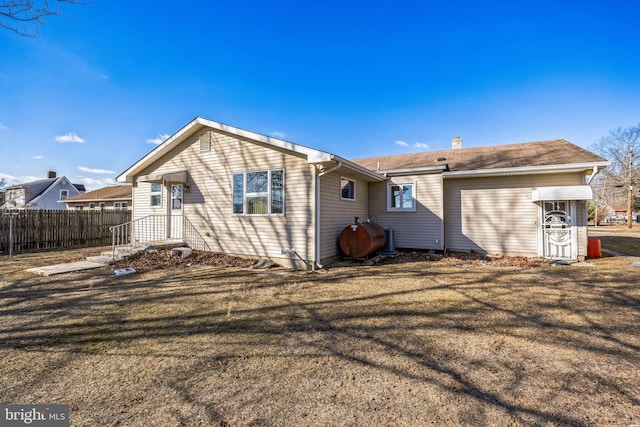 rear view of property with fence and a lawn