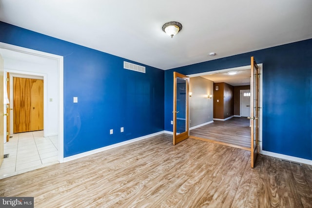 spare room featuring light wood-type flooring, visible vents, and baseboards