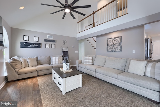 living room with dark hardwood / wood-style floors, ceiling fan, and a towering ceiling