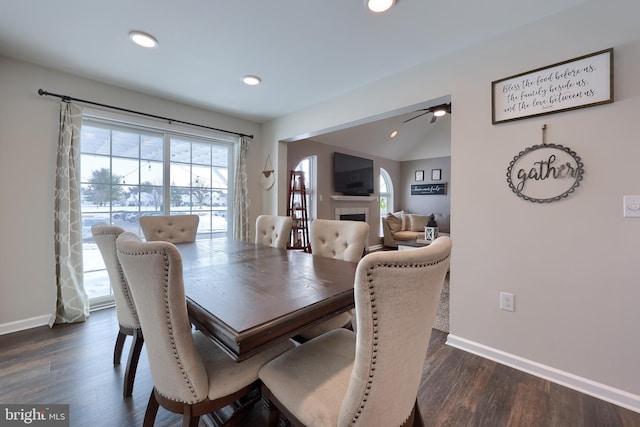 dining space with a tile fireplace, lofted ceiling, and dark hardwood / wood-style flooring