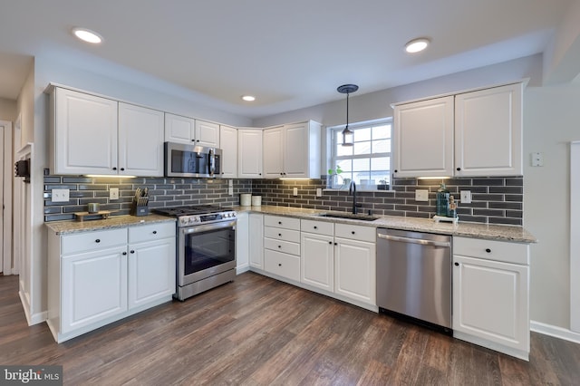 kitchen featuring stainless steel appliances, decorative light fixtures, sink, and white cabinets