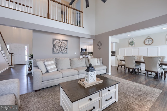 living room with dark wood-type flooring and a high ceiling