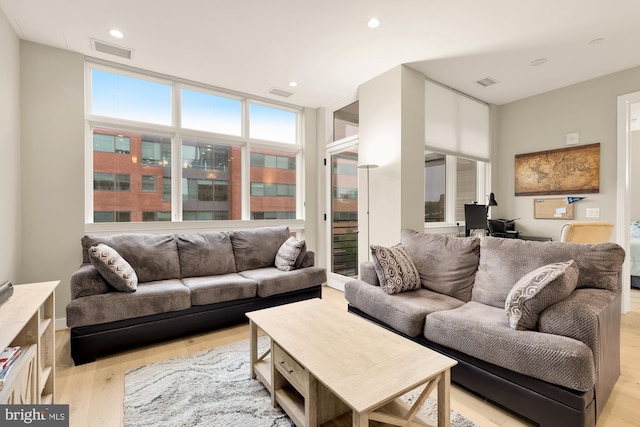 living room featuring a wall of windows and light wood-type flooring