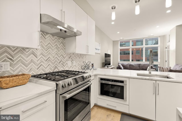 kitchen featuring sink, stainless steel gas stove, oven, decorative backsplash, and white cabinets