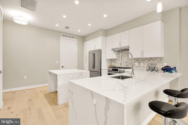 kitchen featuring sink, appliances with stainless steel finishes, tasteful backsplash, a kitchen bar, and kitchen peninsula