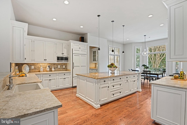 kitchen with sink, a center island, stainless steel microwave, pendant lighting, and decorative backsplash