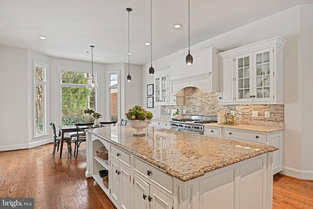 kitchen featuring white cabinetry, decorative light fixtures, and high end stainless steel range