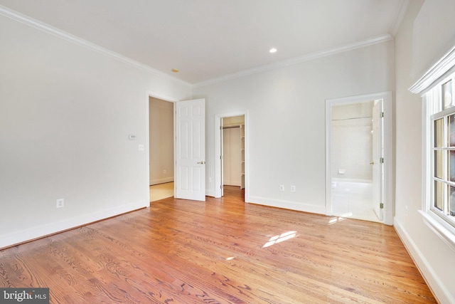 unfurnished bedroom featuring crown molding, a walk in closet, ensuite bath, and light hardwood / wood-style flooring