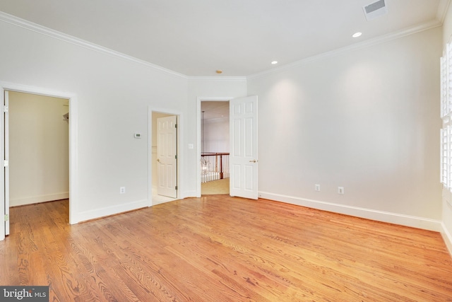 unfurnished bedroom featuring crown molding, a walk in closet, and light hardwood / wood-style flooring