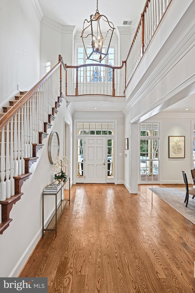 entryway featuring a high ceiling, wood-type flooring, crown molding, and a chandelier