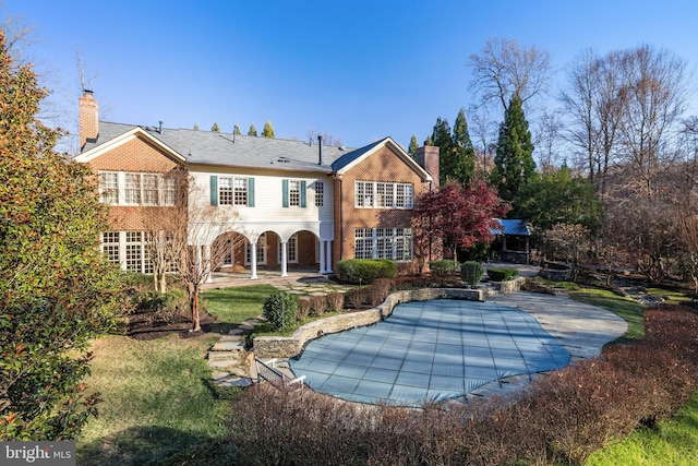 back of property featuring a covered pool and a patio area