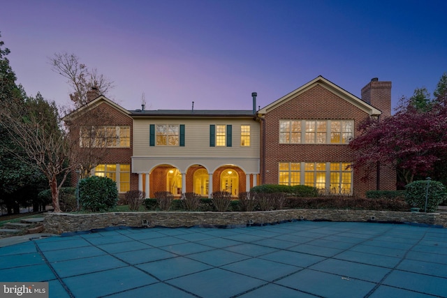 back house at dusk with a patio area and a covered pool