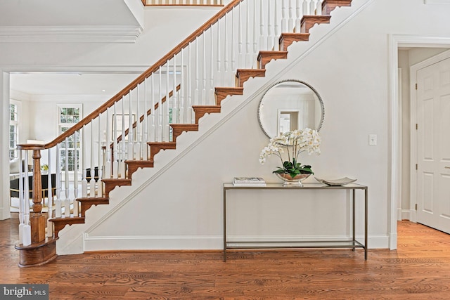 stairs with ornamental molding and hardwood / wood-style floors