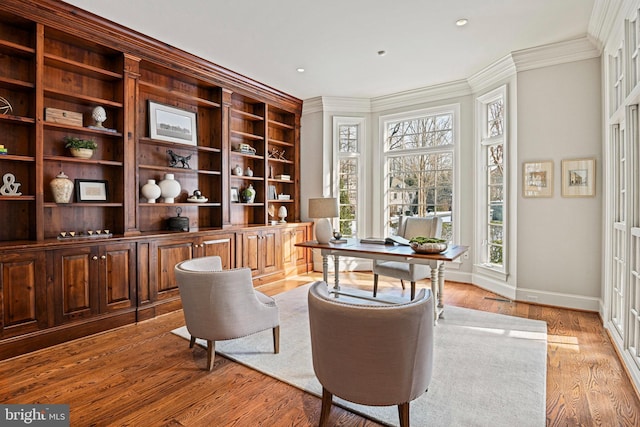 sitting room featuring built in features, ornamental molding, and light hardwood / wood-style floors