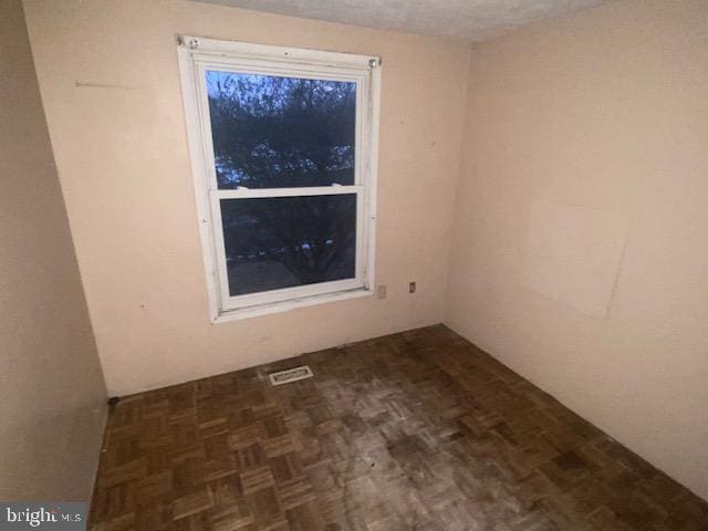 spare room featuring dark parquet flooring