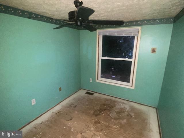 empty room with ceiling fan and a textured ceiling