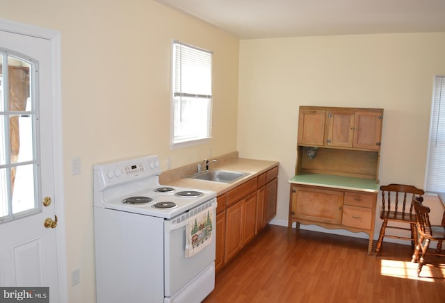 kitchen with white electric range oven, sink, and light wood-type flooring