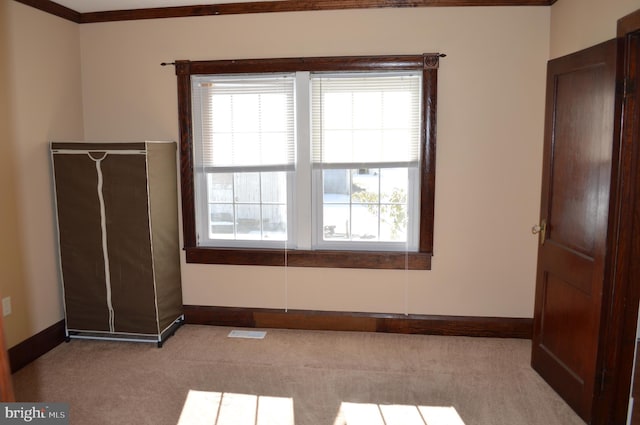 unfurnished bedroom with crown molding, light colored carpet, and multiple windows