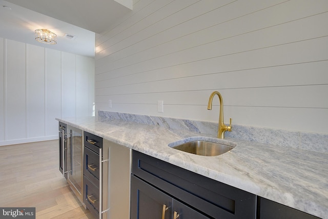 kitchen with sink, light stone counters, and light hardwood / wood-style flooring