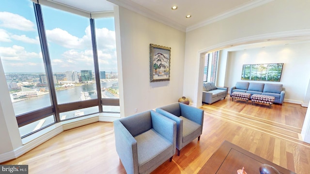 living room featuring hardwood / wood-style floors, crown molding, a wall of windows, and a water view