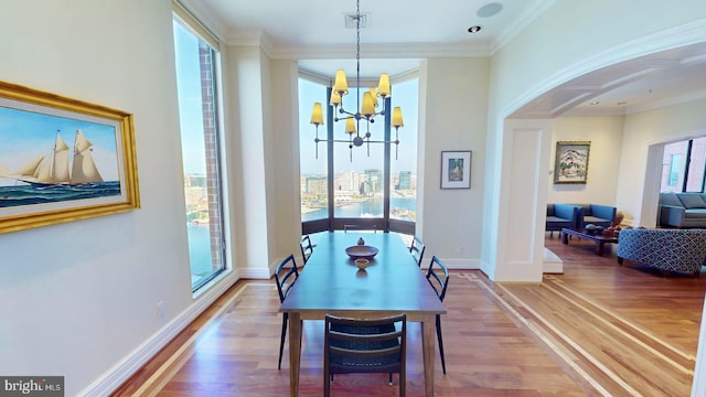 dining area with ornamental molding, wood-type flooring, and a chandelier