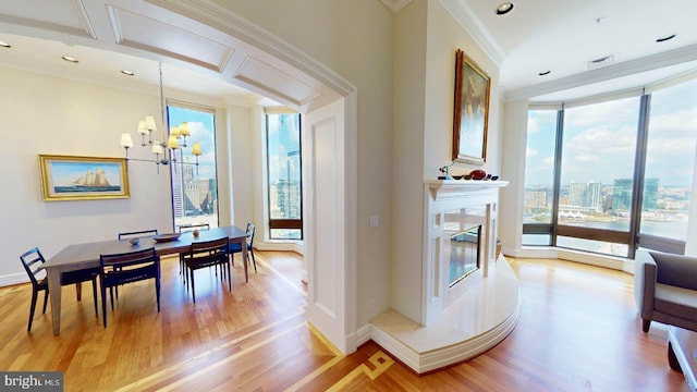 dining space featuring hardwood / wood-style flooring, expansive windows, a high end fireplace, crown molding, and an inviting chandelier