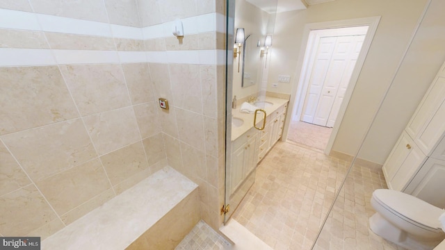 bathroom with vanity, toilet, and a tile shower