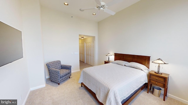 bedroom featuring a high ceiling, light carpet, ceiling fan, and a closet