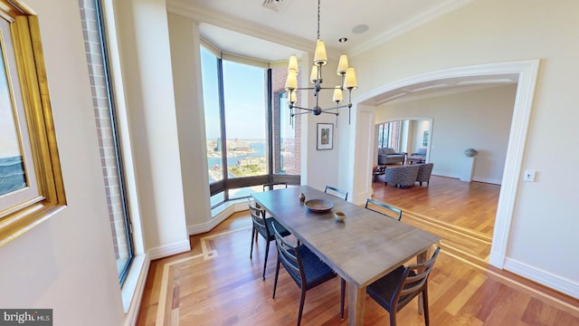 dining space featuring a notable chandelier, ornamental molding, and light wood-type flooring