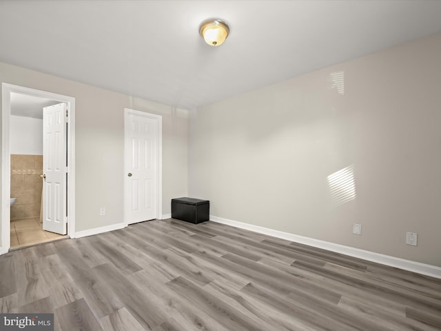 unfurnished bedroom with connected bathroom and light hardwood / wood-style floors