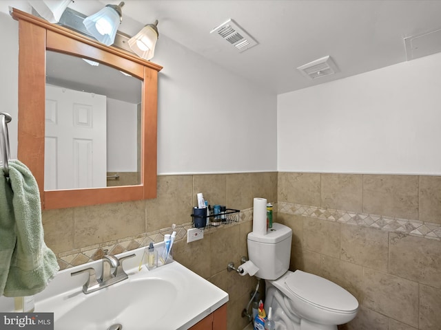 bathroom with vanity, tile walls, and toilet