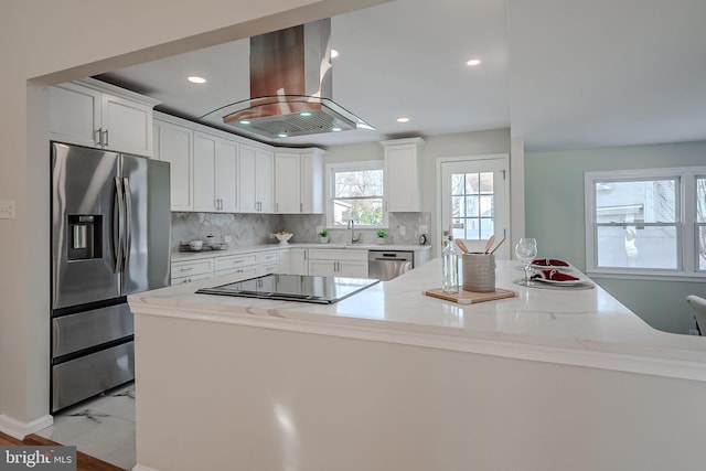 kitchen with white cabinetry, island range hood, stainless steel appliances, and light stone countertops