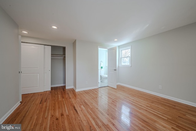 unfurnished bedroom with ensuite bath, light hardwood / wood-style floors, and a closet