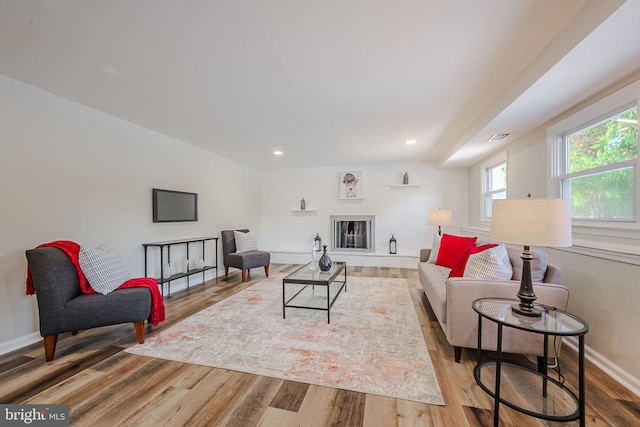 living room with hardwood / wood-style flooring and a brick fireplace