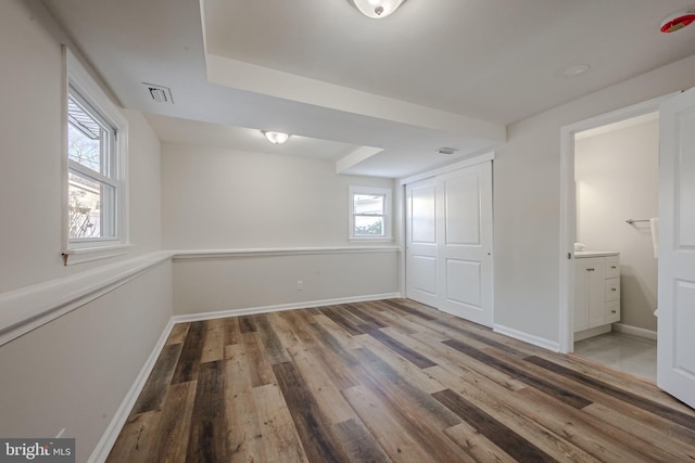 unfurnished bedroom featuring hardwood / wood-style flooring, connected bathroom, and a closet