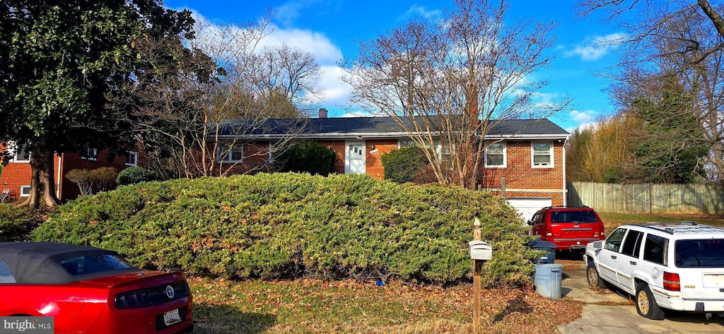 ranch-style house featuring brick siding, fence, and a chimney