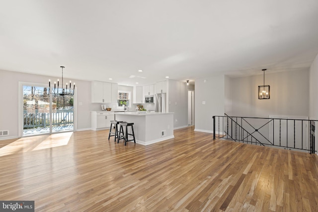 unfurnished living room with a healthy amount of sunlight, light hardwood / wood-style flooring, and a chandelier