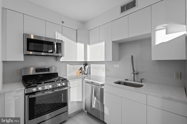 kitchen with tasteful backsplash, stainless steel appliances, and white cabinets