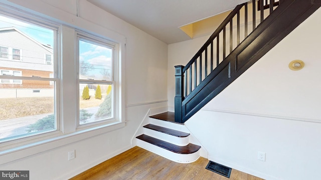 stairs featuring hardwood / wood-style flooring and plenty of natural light