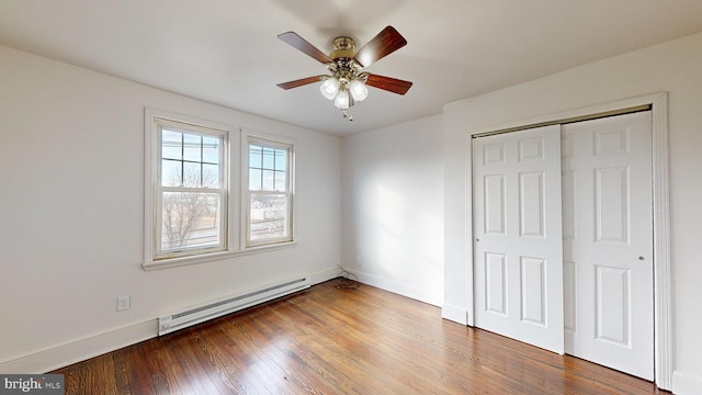 unfurnished bedroom with a baseboard radiator, wood-type flooring, ceiling fan, and a closet