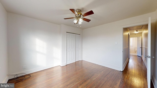 unfurnished bedroom featuring ceiling fan, dark hardwood / wood-style flooring, and a closet