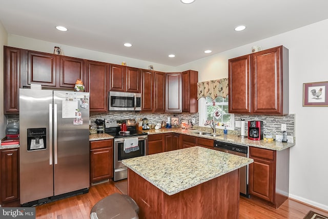 kitchen with sink, backsplash, hardwood / wood-style flooring, a center island, and stainless steel appliances