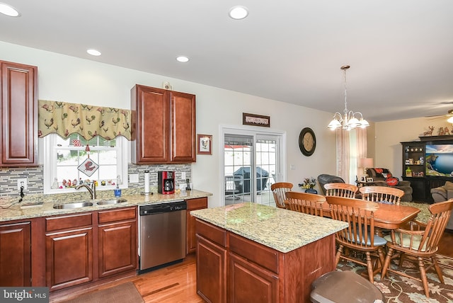 kitchen with a kitchen island, decorative light fixtures, sink, stainless steel dishwasher, and light stone countertops