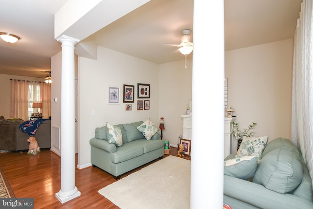 living room featuring ceiling fan, wood-type flooring, and ornate columns